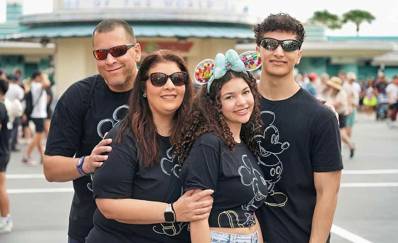 A family of four wearing matching black Mickey Mouse t-shirts at Disney